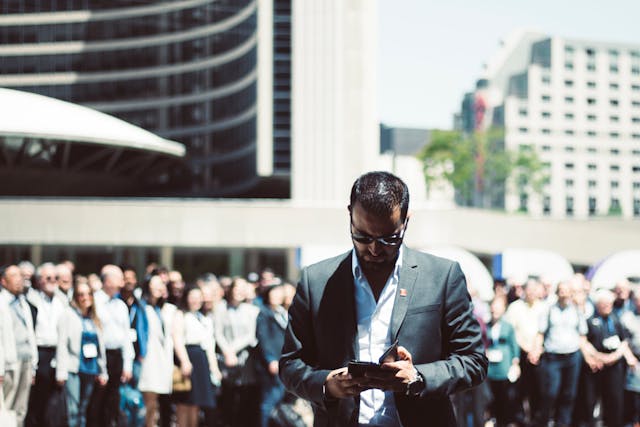 man-holding-smartphone-while-standing-near-people